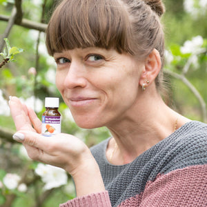 Frau mit ätherischen Mandarinen-Öl in der Hand im Garten