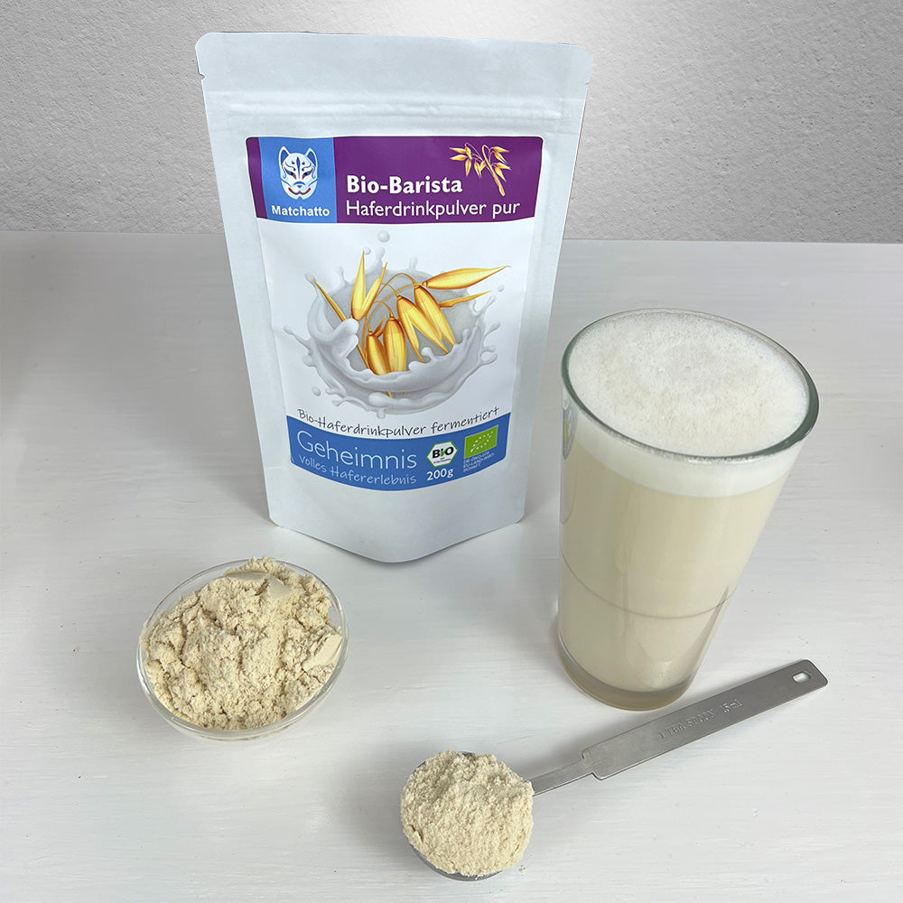 Haferpulver in einer Schale mit Beutel, Löffel und Haferdrink im Glas