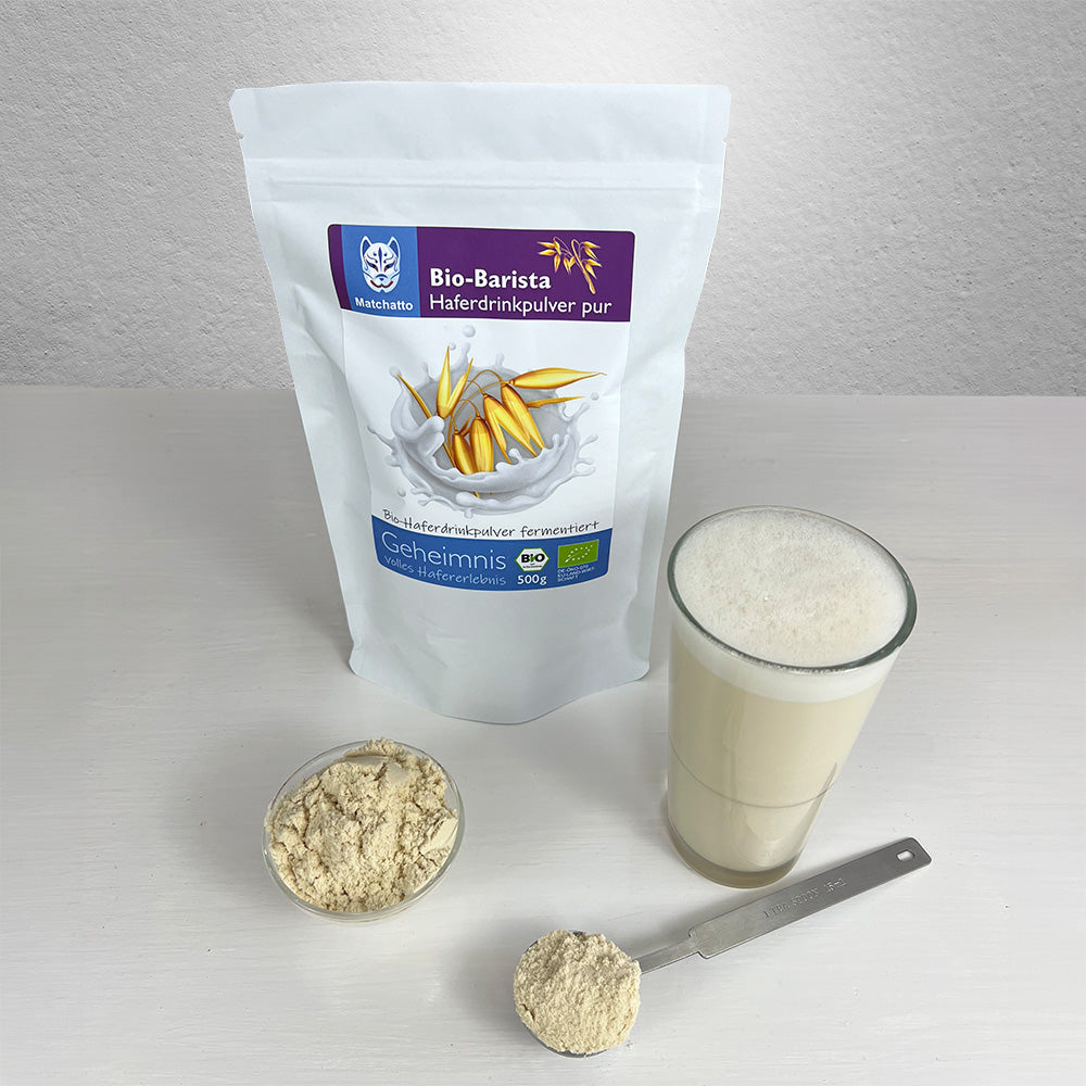 Haferpulver in einer Schale mit Beutel, Löffel und Haferdrink im Glas