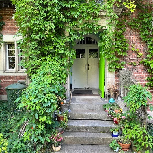 Matchatto Firmenstandort in Berlin-Buch – grüner Eingangsbereich der Villa Hufeland, umgeben von Natur und Pflanzen