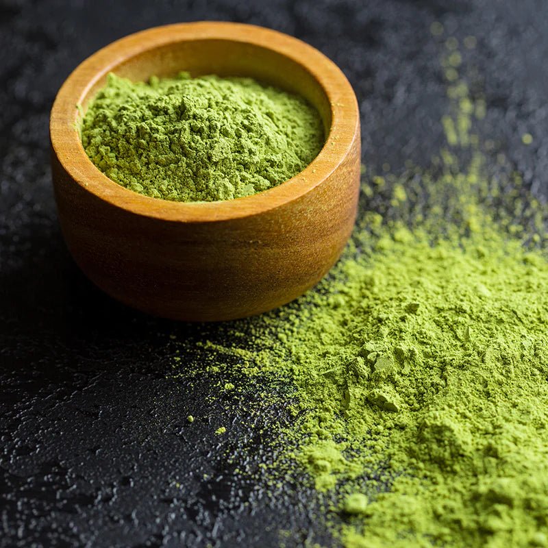 Frisches Bio-Matcha-Pulver in einer Holzschale auf dunklem Untergrund – fein gemahlen und aromatisch grün.