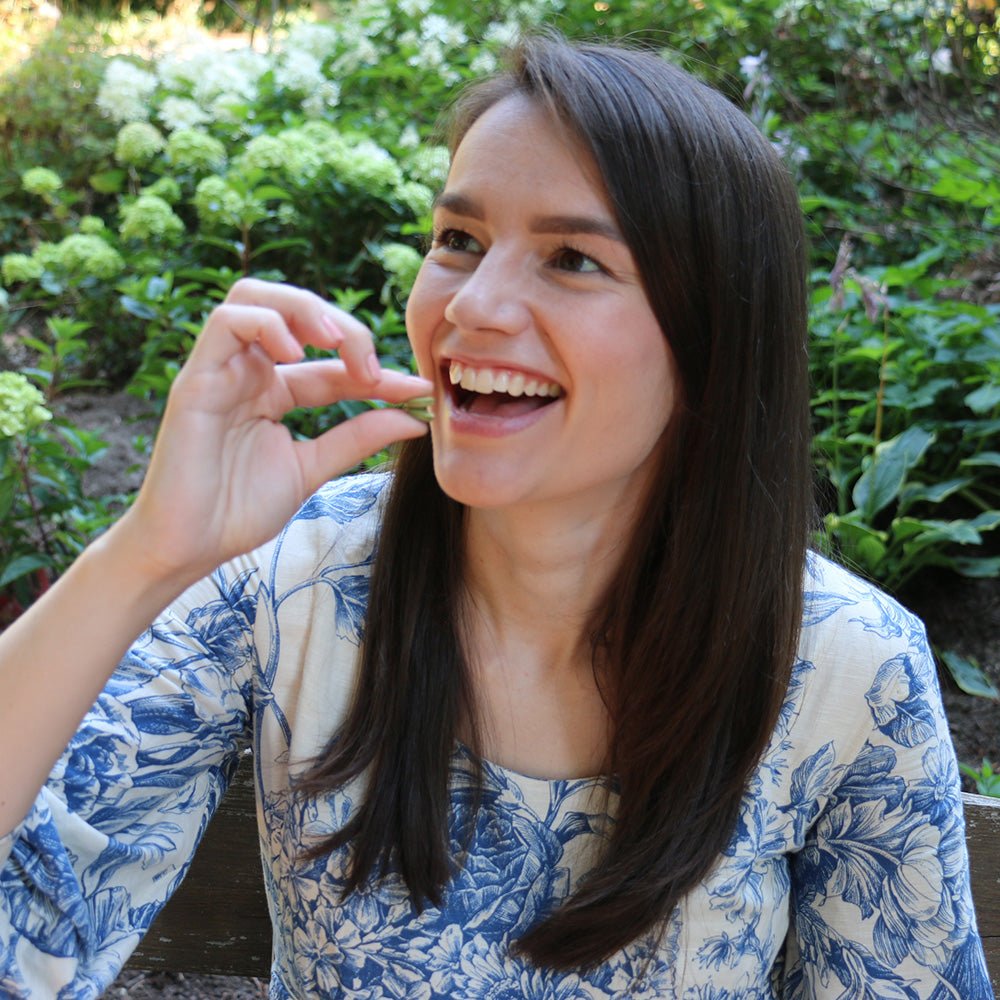 Eine Frau hält gutgelaunt Bio Matcha Drops in der Hand