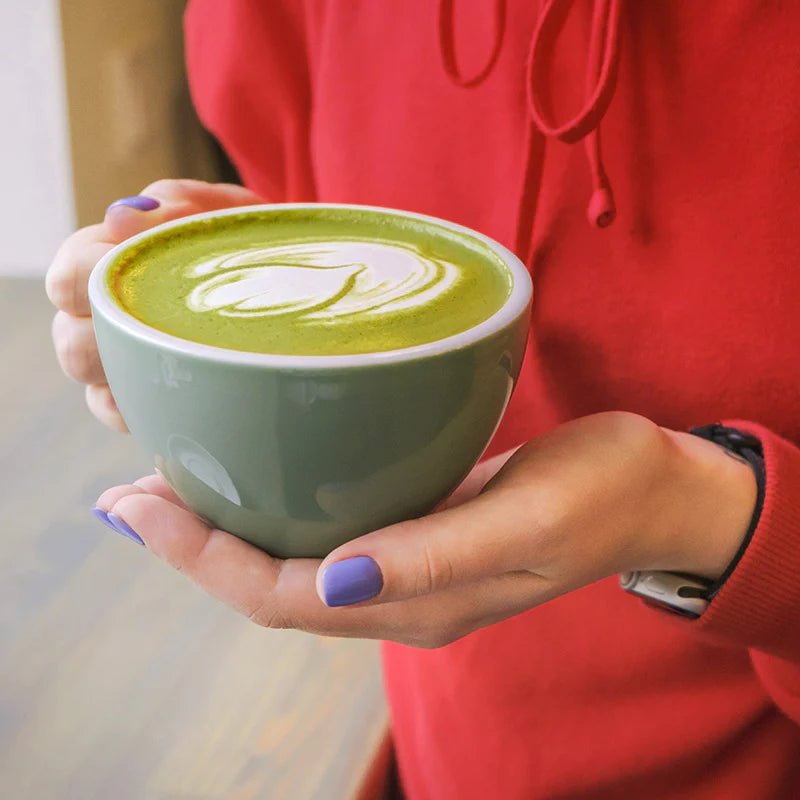 Matcha Latte in Matcha Schale mit Frauenhand